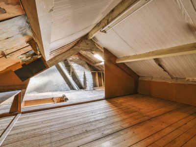 The interior of a spacious empty space with wooden floors in the attic of a cozy house