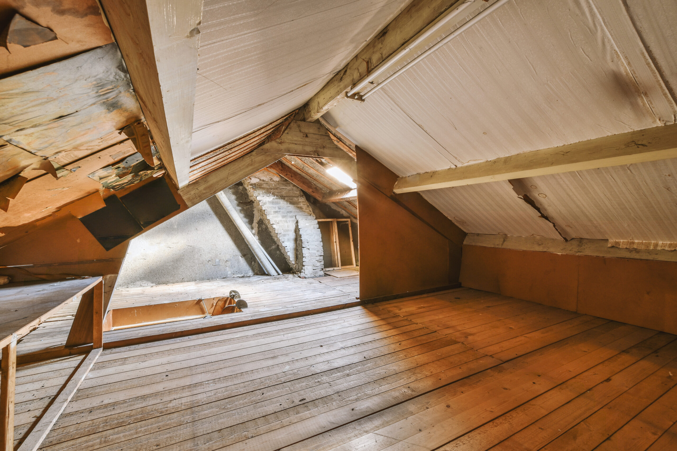 The interior of a spacious empty space with wooden floors in the attic of a cozy house